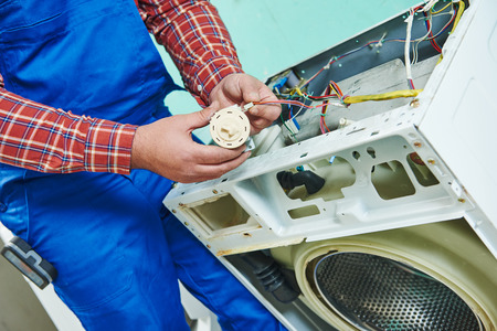 repairman fixing a washer and dryer unit